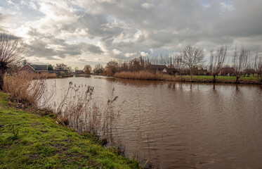 Fototapeta premium Dutch landscape on a cloudy day in the winter season. The photo was taken near the village of Giessenburg on the river Giessen, province of South Holland.