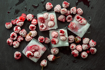 Obraz na płótnie Canvas Raspberries and ice cubes. Ice prepared for summer drinks and cocktails. Frozen berries on a dark textured background.