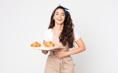 pretty woman laughing out loud at some hilarious joke and holding a croissants tray