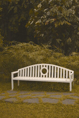 A white bench in a park is taken from the front angle