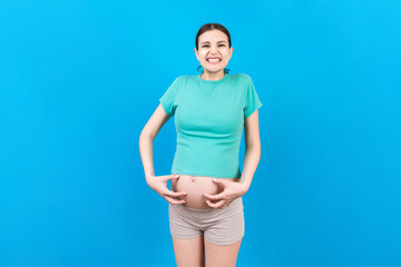 Fototapeta na wymiar Pregnant woman scratching her belly on colored background