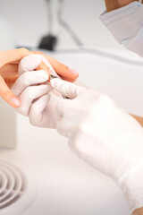 Obraz na płótnie Canvas Close up of manicure master with manicure nipper cuts cuticles of female nails at beauty salon