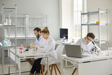 Group of medical scientists doing research in modern pharma or biotech science laboratory. Busy men...