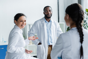 Fototapeta premium African american doctor talking to colleague on blurred foreground in clinic