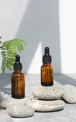 Bottles of dark amber glass of lotion or essential oil on gray stones. Natural SPA cosmetic...