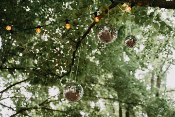 Discokugel und Lichterkette hängen an Baum