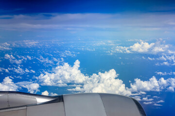 Fototapeta na wymiar Above the Clouds - Aerial View of Blue Sky and Fluffy Clouds from the Aeroplane Window during Flight