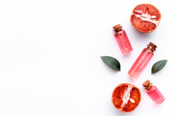 Grapefruit fragrance essential oil in bottles with fresh fruits. Top view