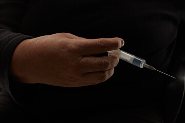 Woman hand with a syringe isolated on black background