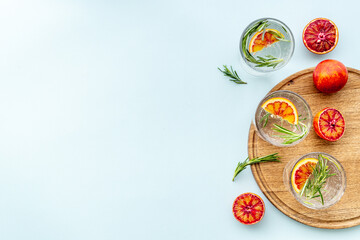 Red orange lemonade in glasses with ice and rosemary