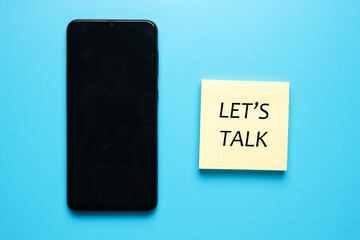 Smartphone and the the word let's talk on notepad. Commmunication and problem solving concept.
