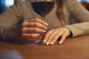 Hand of a young beautiful woman holding a glass of wine indoors of a stylish wine restaurant