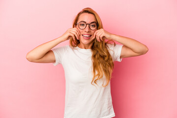 Caucasian blonde woman isolated on pink background doubting between two options.