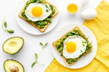 Breakfast with avocado toasts and fried eggs, top view