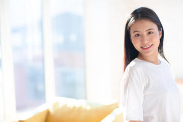 Portrait of smiling asian woman on apartment interior background with copy space