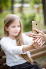 beautiful girl in a white blouse with a phone on a bench