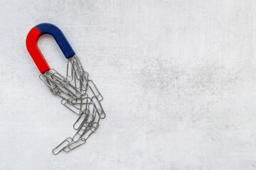 Fototapeta premium Horseshoe magnet collecting paper clips. Office supplies top view