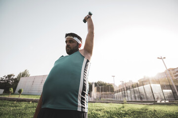  a fat boy lifting a dumbbell in an outdoor park. willpower