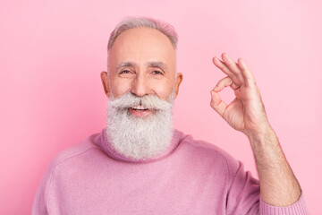 Portrait of positive grey hair senior man show okey sign wear pink sweater isolated on pastel color background