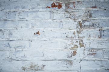 White painted old brick wall with red cracked bricks.