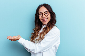 Young mexican woman isolated on blue background holding a copy space on a palm.
