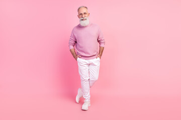 Photo of cute charming mature man dressed pullover glasses smiling walking arms pockets isolated pink color background