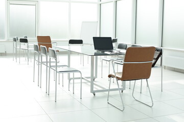 Flipchart laptop chairs glass table in a bright office space