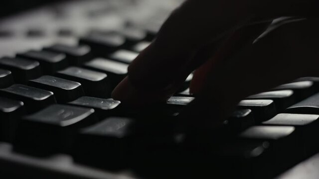 Computer keyboard close-up with fingers playing game using WASD keys.