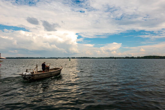 A Small, Outboard Powered, Boat Heads Out On A Harbour In Summer. Banner