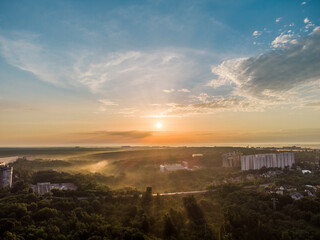 Aerial sunrise morning cloudy skyscape. Multistory buildings and greenery with fog at dawn in nice pastel light. View on Sokilnyky with bridge across Sarzhyn Yar in Kharkiv city.