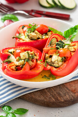 Baked peppers stuffed with vegetables in a plate on a gray concrete background. Baked peppers with zucchini, avocado, tomatoes and basil. Vegan or diet food.