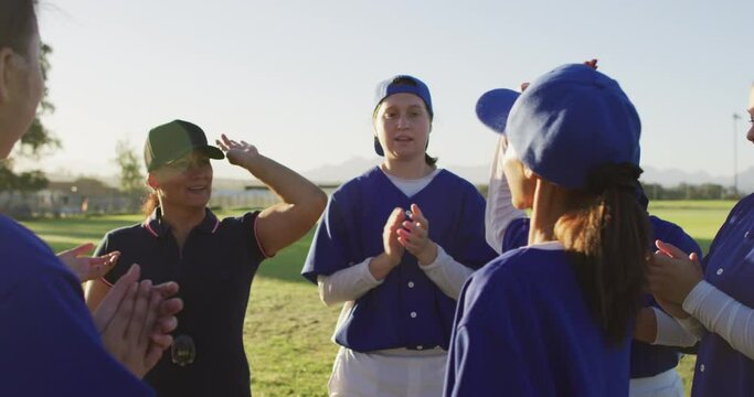 Diverse Group Of Female Baseball Players And Coach On Pitch, Clapping And High Fiving