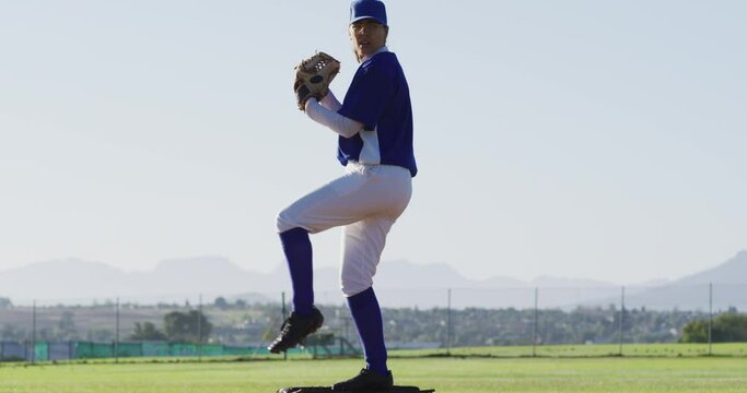 Caucasian female baseball player wearing glasses pitching ball on baseball field