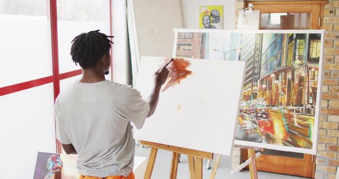 African american male painter painting on canvas in artist studio