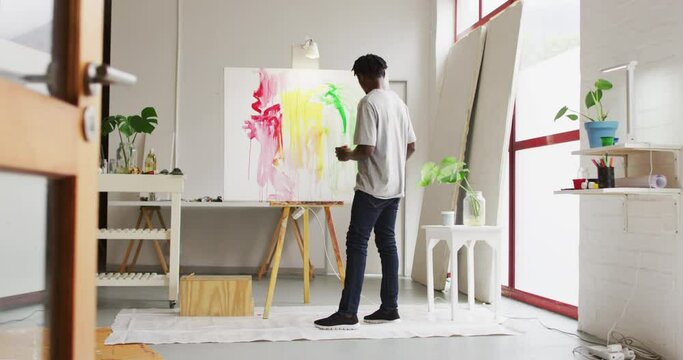 Rear view of african american male artist painting on canvas at art studio