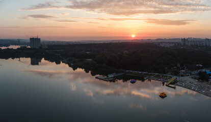 Scenic aerial sunrise with clouds reflecting in mirror water surface on wide river. Early morning, dawn in Kharkiv Zhuravlivskyy Hidropark from sky