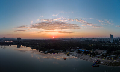 Scenic aerial sunrise with clouds reflecting in mirror water on river. Early morning, dawn in Kharkiv Zhuravlivskyy Hidropark beach from sky. Drone photography