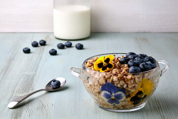 Whole grain oatmeal in a glass bowl with blueberry