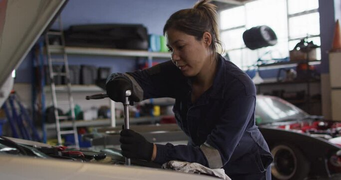 Female mechanic using a wrench to repair a car at a car service station