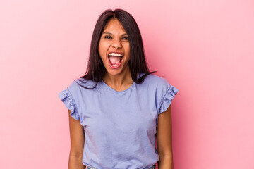 Young latin woman isolated on pink background shouting very angry, rage concept, frustrated.