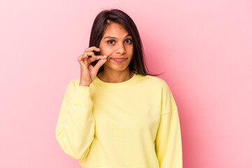 Young latin woman isolated on pink background with fingers on lips keeping a secret.