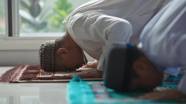 Asian Muslim father and son praying in the evening at his home during the month of Ramadan, 4k resolution.