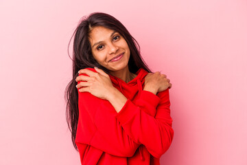 Young latin woman isolated on pink background hugs, smiling carefree and happy.