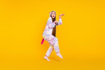 Fototapeta na wymiar Full length body size photo childish girl wearing unicorn pajama walking quietly isolated vivid yellow color background