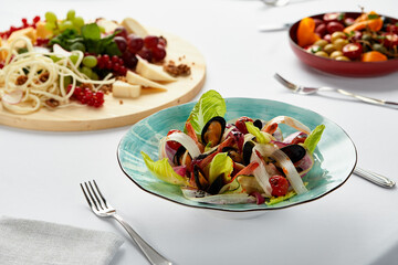 Mussels vongole with salad, mussels cooked in white wine sauce, mussel appetizer on the table surrounded by a selection of cheeses and other snacks