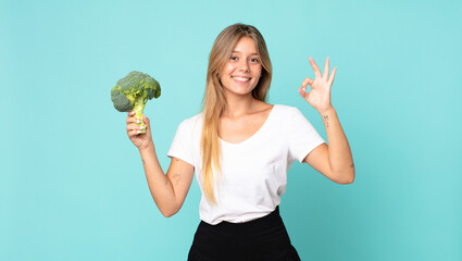 pretty young blonde woman holding a broccoli