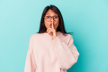 Young latin woman isolated on blue background keeping a secret or asking for silence.