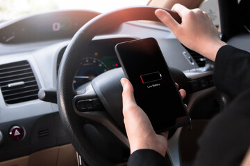 A young woman driving a car. I am using my phone but my battery is running low.