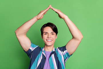 Photo of cool brunet young guy hands up wear striped shirt isolated on green color background