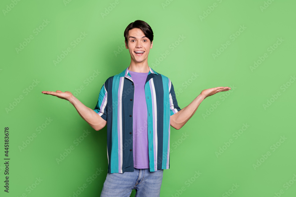 Sticker Photo of amazed happy excited happy man hold hands empty space scales isolated on green color background